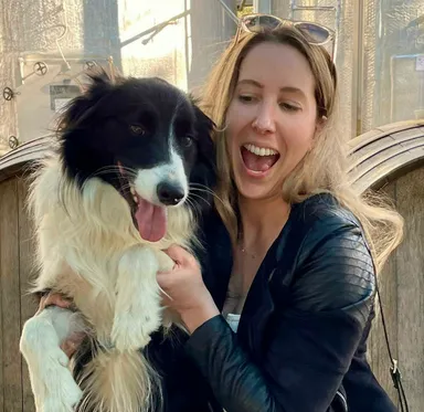 Kaisha Jones laughing while holding Louis, the family's black and white Border Collie