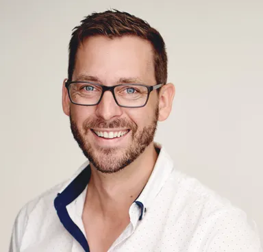 Portrait of Reid Jones, podiatrist and owner of Clare Valley Podiatry, smiling in a white shirt and glasses
