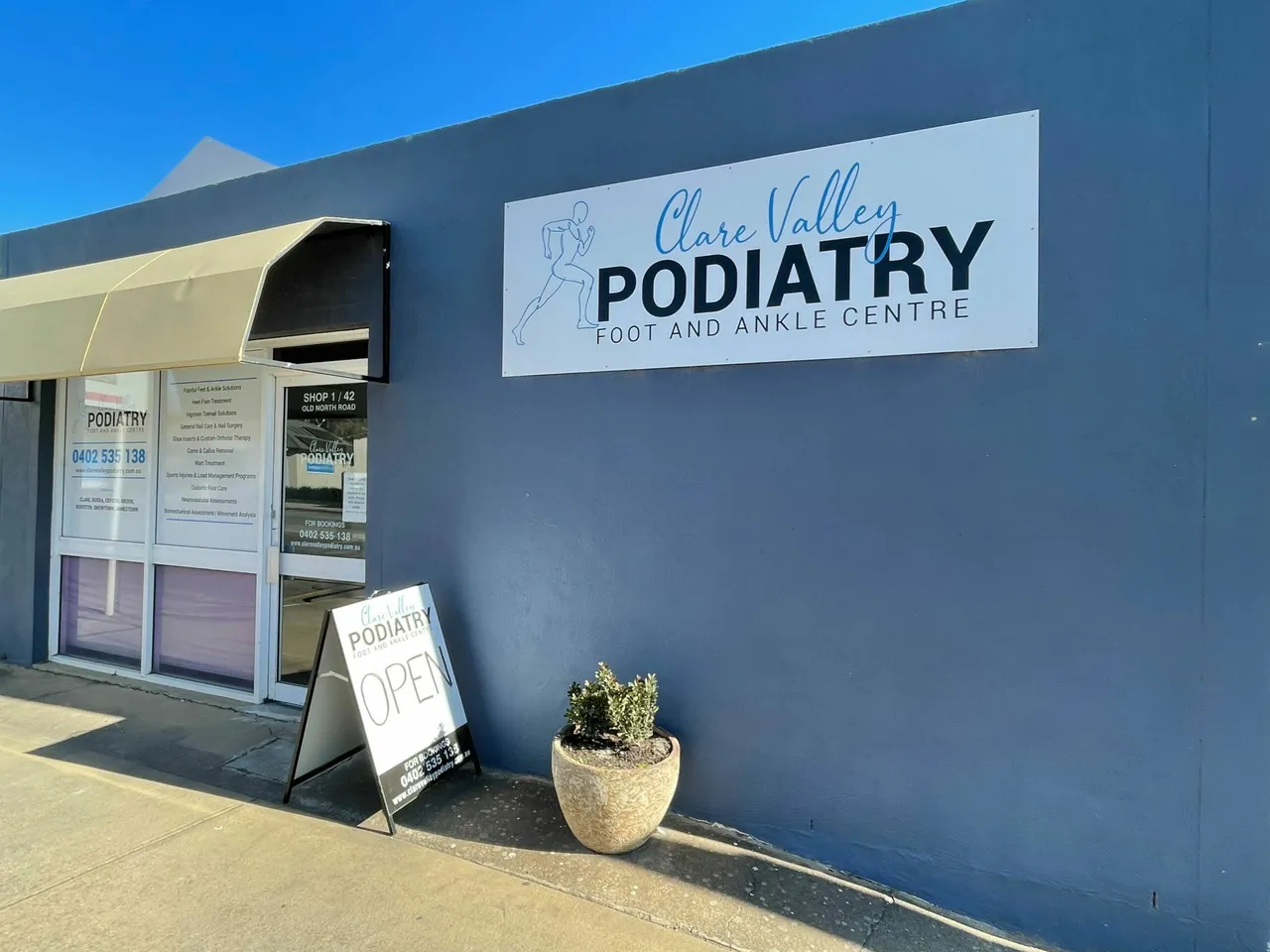 The Clare Valley Podiatry shop front under a blue sky, with an Open sign on the footpath