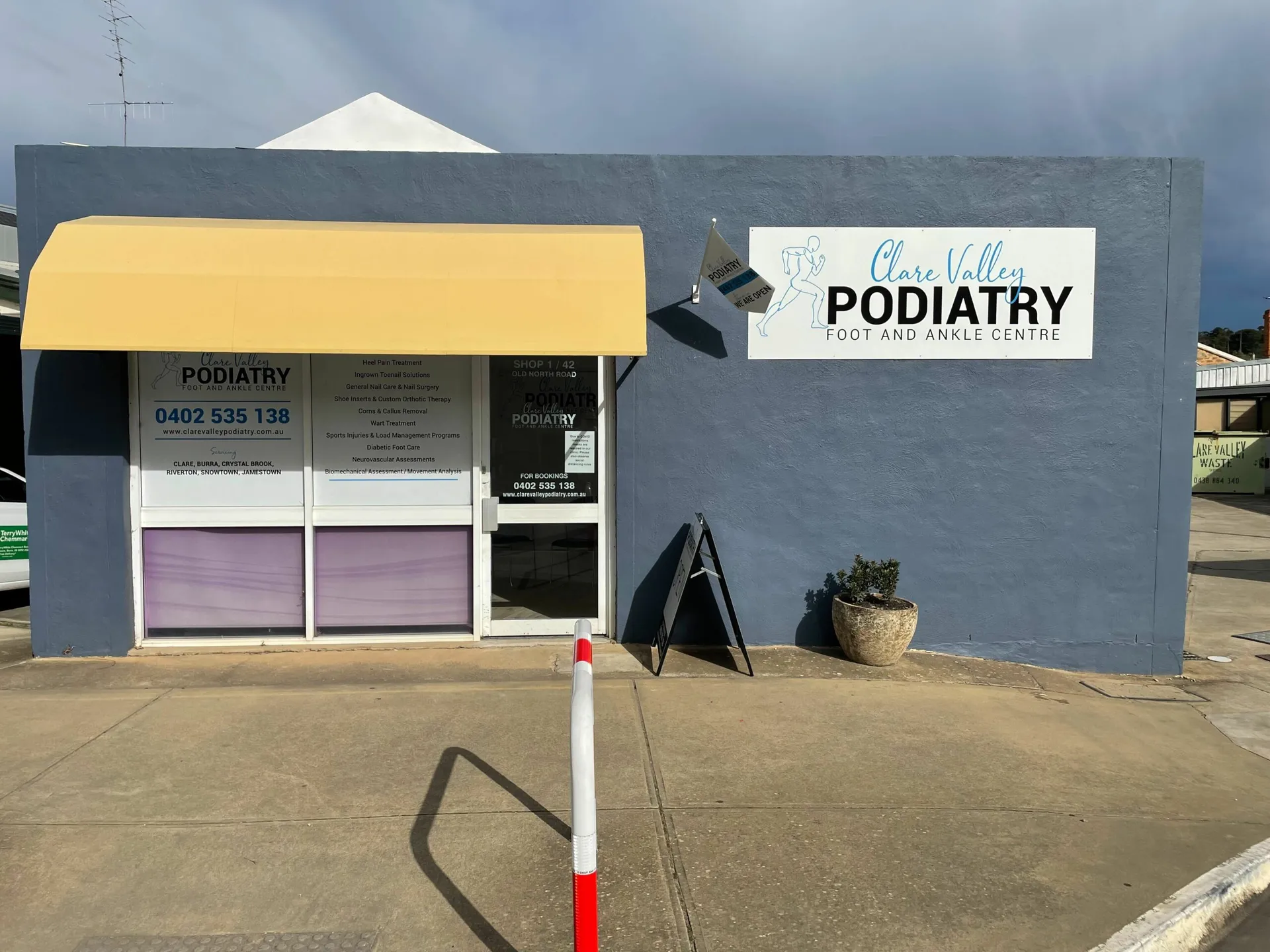 The Clare Valley Podiatry shop front on Old North Road, with its yellow awning and a flag beside the sign